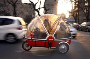 A woman and her son sit inside the capsule of an electric tricycle as they drive along a main road in central Beijing - March 15, 2012