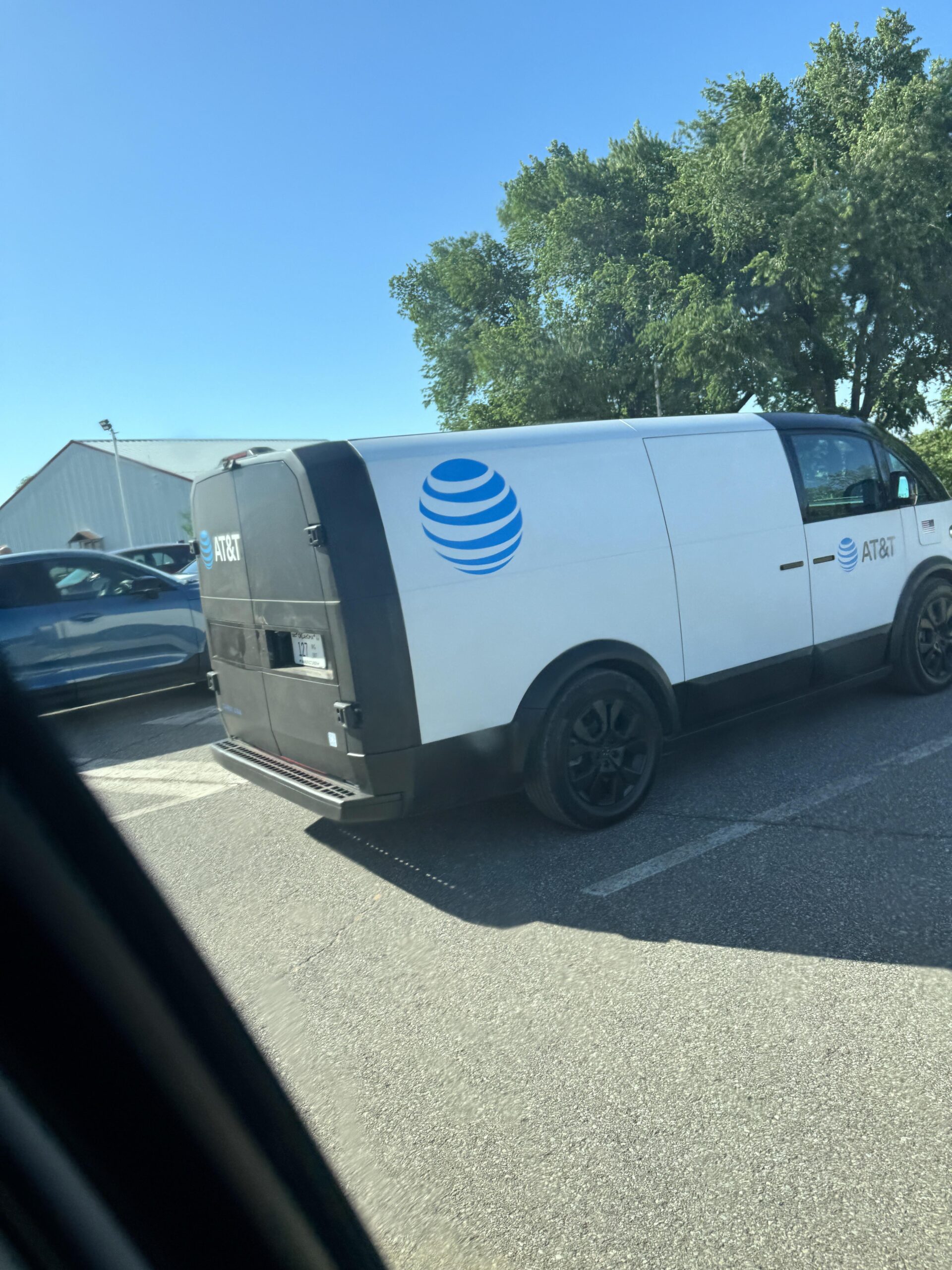 AT&T wrapped Canoo EV utility van in parking lot - EVSHIFT