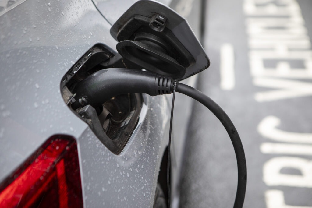 Raindrops on the bodywork of an electric car parked in an electric vehicle charging bay on a London street