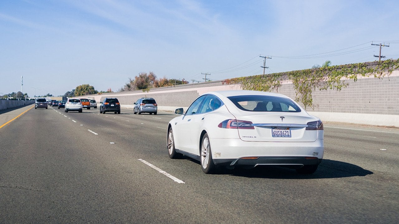 A white Tesla Model S driving on a freeway in San Francisco, California.