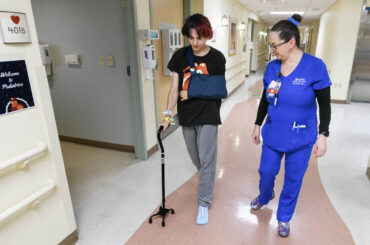 Mason Huff is assisted by nurse Vida Mia Golembeski at he walks down the hallway at Sunrise Hos ...