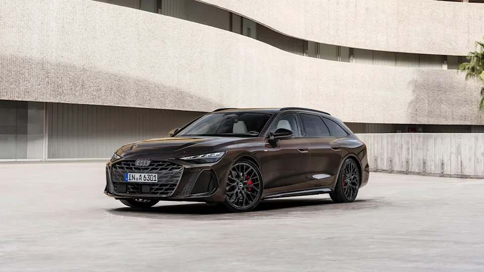 The new Audi A6 Avant in brown next to a concrete building, front 3/4 view