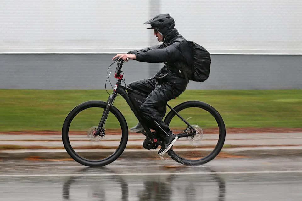 A man rides his e-bike down JFK Memorial Highway in New Bedford on a rainy morning.