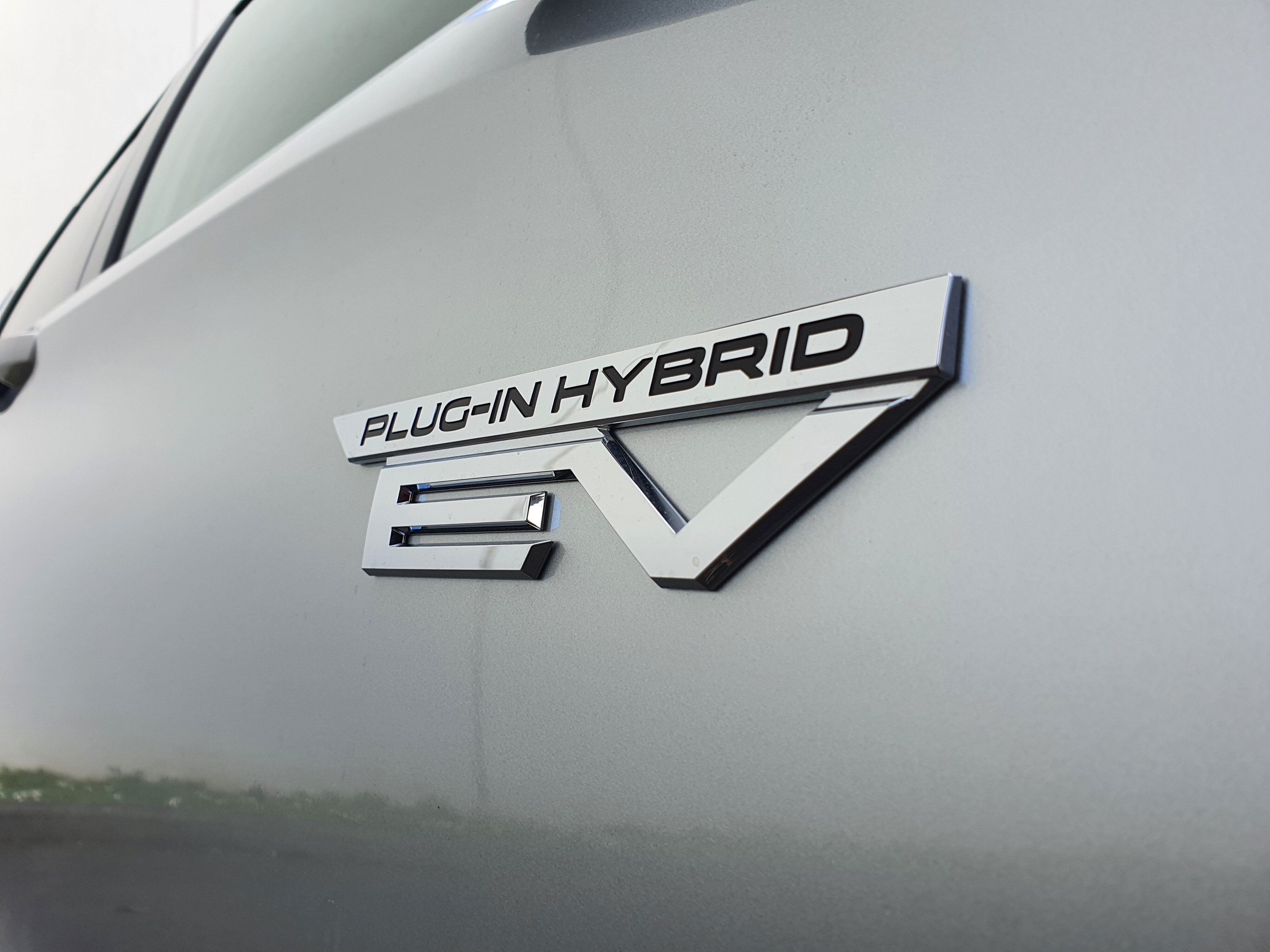 A photo of the Plug-in Hybrid EV badge on the side of a 2025 Mitsubishi Outlander VRX PHEV in silver. 