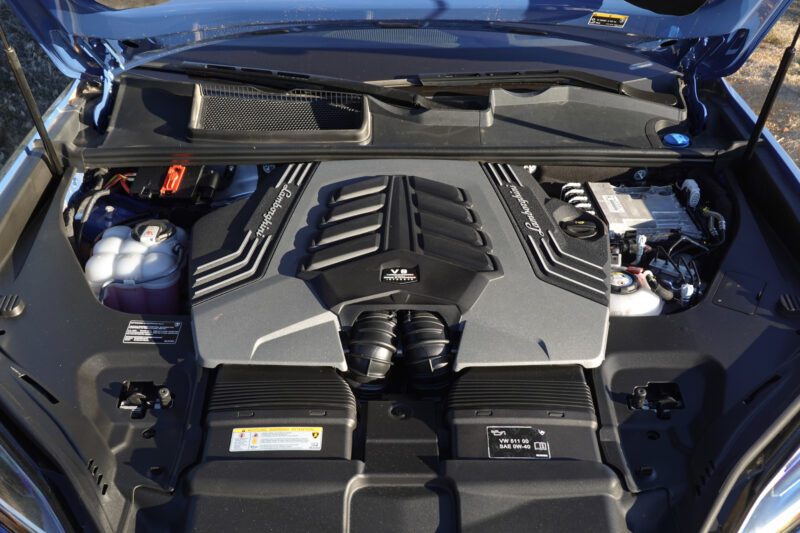 A close-up view of a V8 Biturbo engine under the hood, highlighting key components and fluid reservoirs in the 2025 Lamborghini Urus SE Review: Heavy Hitter Delivers Plug-In Hybrid Punch.