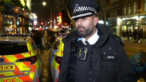 Commander Neerav Patel in uniform on a busy London street at night. 