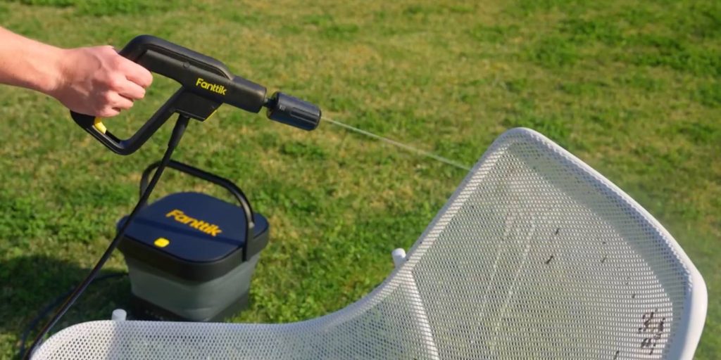 man using Fanttik cordless electric pressure washer to clean patio furniture