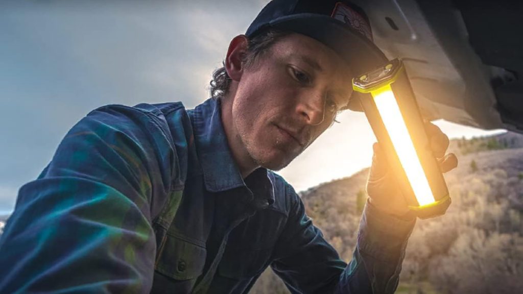 man using Goal Zero Torch 500 multi-purpose light while working on car