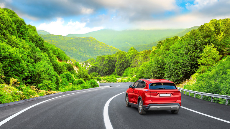 A red electric SUV driving on a winding road.