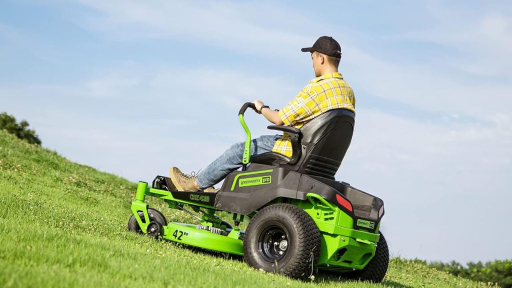 man mowing grassy hill on Greenworks riding lawn mower