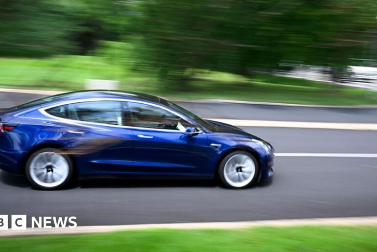 A Tesla vehicle drives off the lot at the company's store in Warminster, Pennsylvania, US, on Tuesday, July 22, 2025.