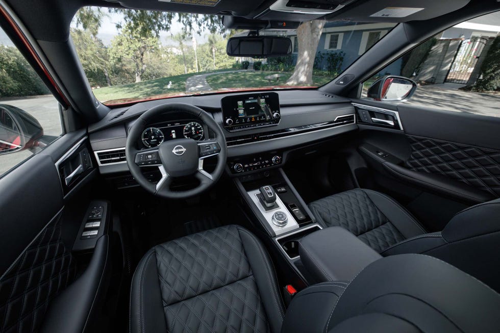 driver side view of black quilted leather seats, steering wheel, center console, and dashboard display.