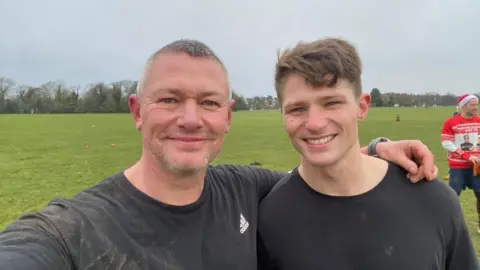 Mark Rowlands Mark Rowlands, a man with short grey hair, poses with his son Declan who has brown hair. They are standing together in a park, smiling. 
