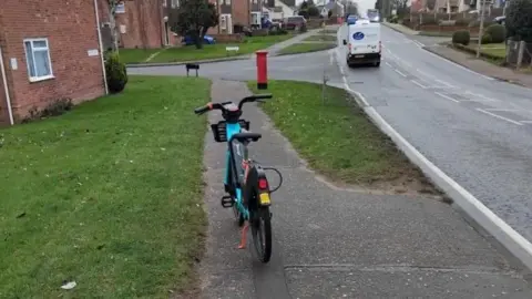 Paul Horwood E-bike left on a path in Colchester - it is standing on a kick stand and is bright blue