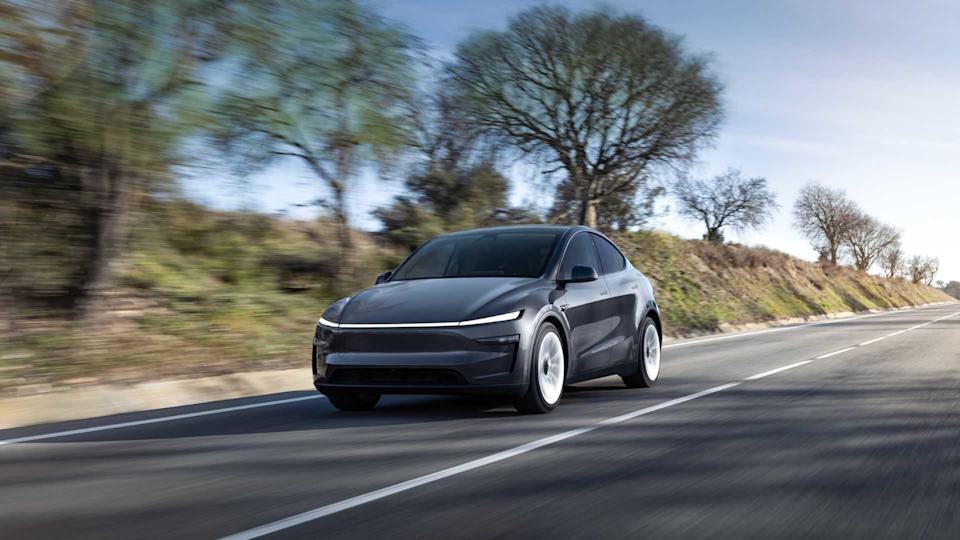 Dynamic frotn 3/4 shot fo a gray new Tesla Model Y driving on a country road.