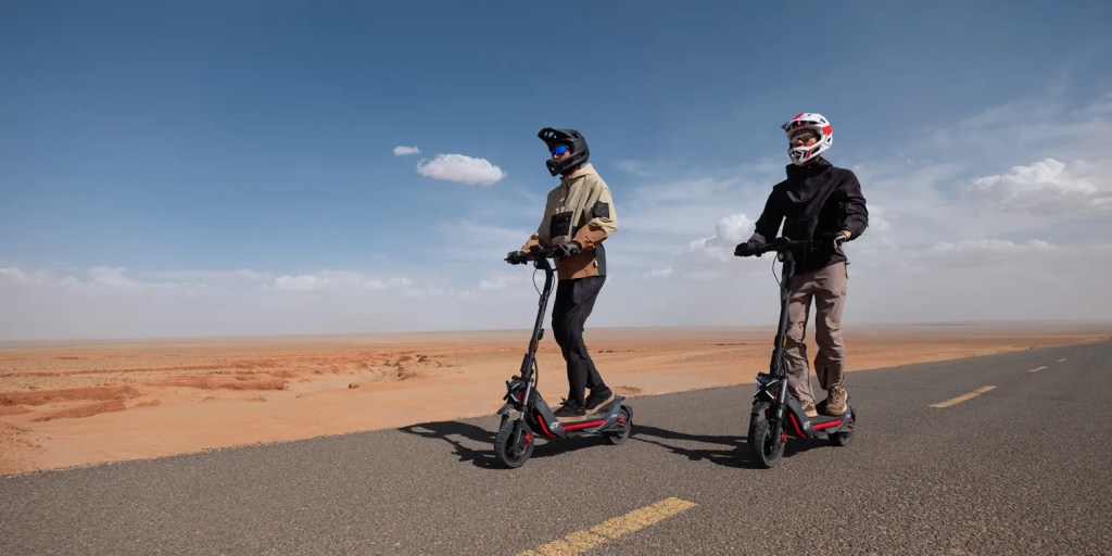 Two men riding Segway ZT3 Pro electric scooter down desert road