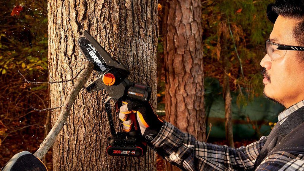 man using Worx mini chainsaw to prune tree branch