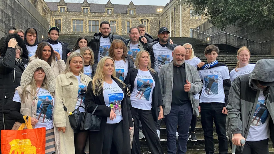 A group of 22 people standing on the steps of Winchester Crown Court. Nearly all of them are wearing white t-shirts printed with pictures of Joey Johnston which read Justice for Daddy and Justice for Joey.