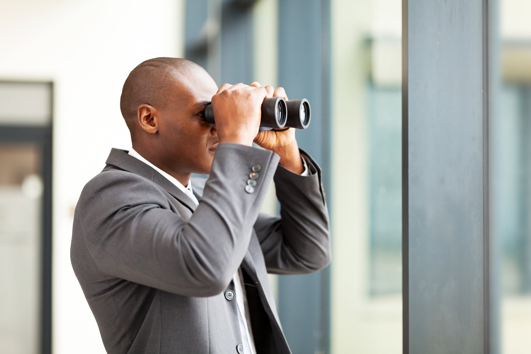 A person looks into the distance using a pair of binoculars.