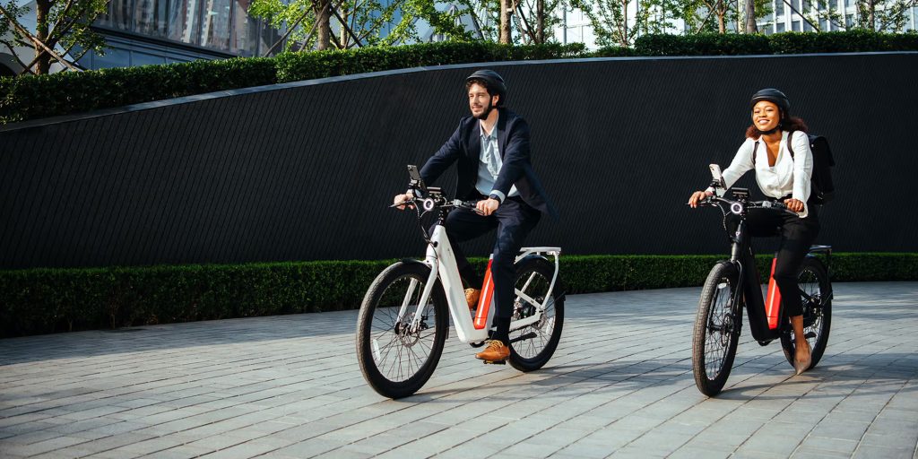 man and woman riding on NIU e-bikes down walkway