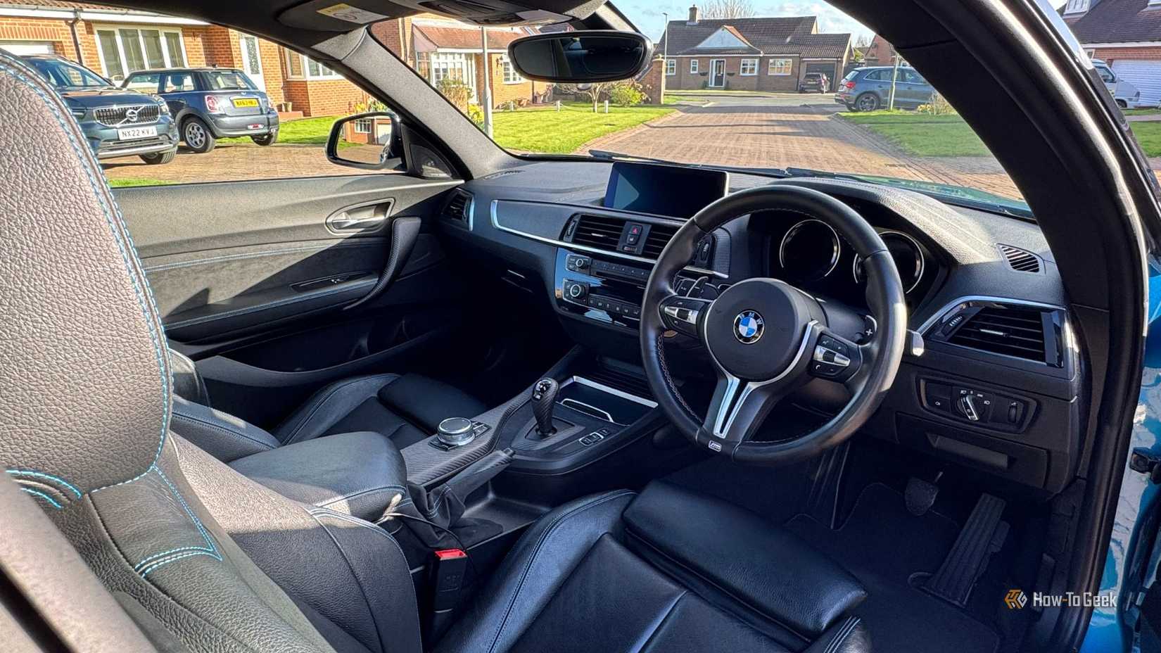Close-up shot of inside the cabin of a 2018 BMW M2, showing the front seats, steering wheel, and infotainment screen.