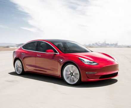 Full view of a red 2018 Tesla Model 3 driving on an airfield.