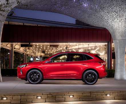 Static side profile shot of a red 2023 Ford Escape ST-Line Elite parked outside of a modern building.