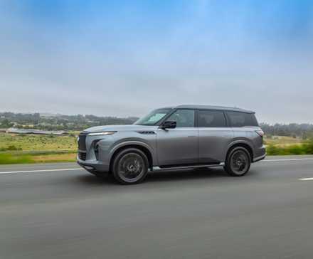 2025 Infiniti QX80 driving on the highway with the Dynamic Metal paint.