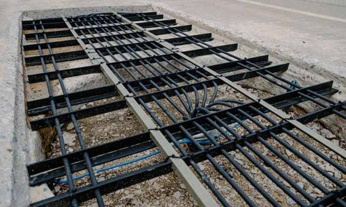Close-up of wireless charging transmitter coils embedded beneath a section of concrete roadway.