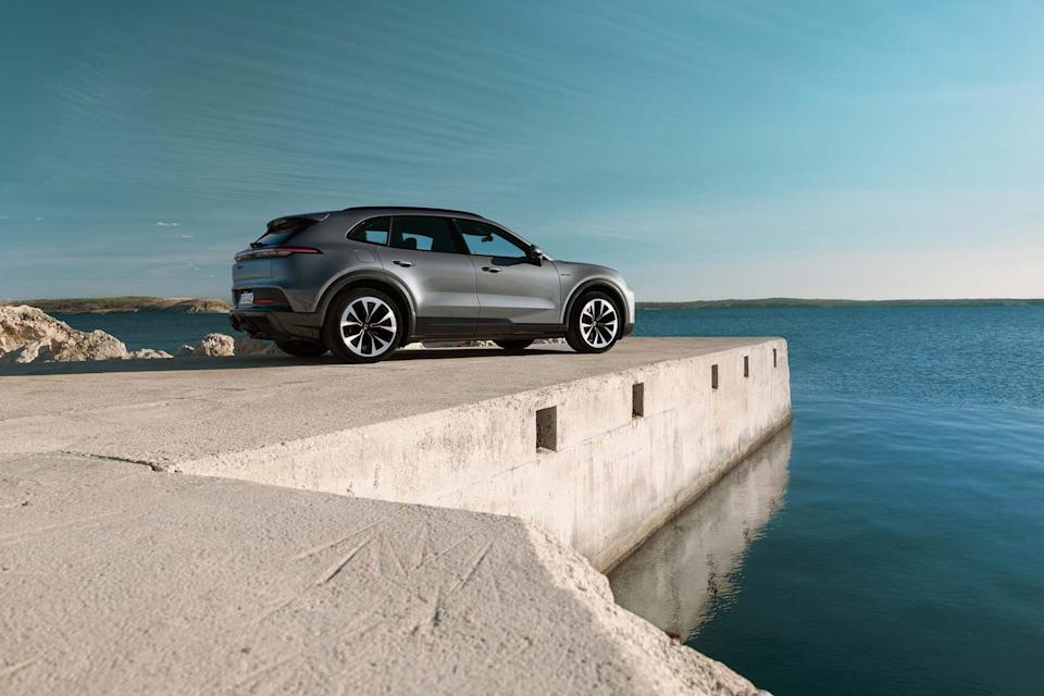 rear three quarter view of silver suv parked on concrete pier beside calm ocean water.