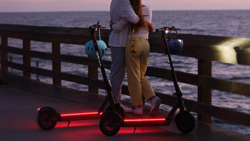 couple hugging on boardwalk with Hiboy e-scooters