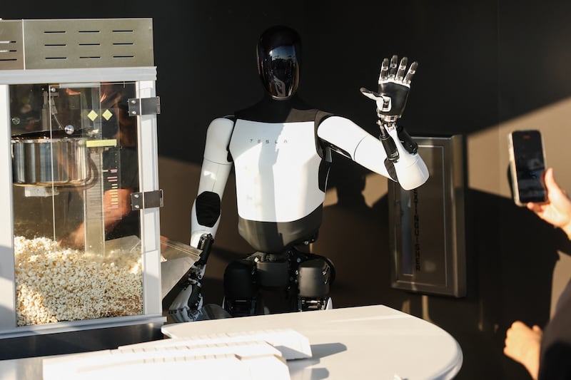 A Tesla Optimus robot scoops popcorn and waves at attendees of the Tesla Diner and Drive-In restaurant in California last July. Photograph: Patrick T Fallon/AFP via Getty Images