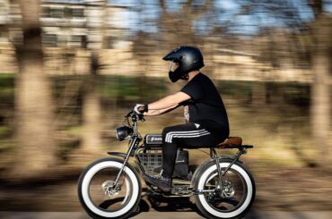 A man wearing a masked helmet riding an electric bike.