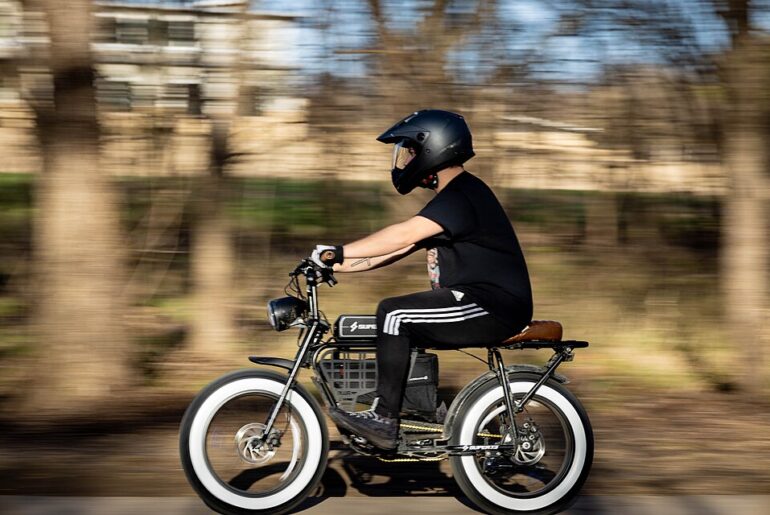 A man wearing a masked helmet riding an electric bike.