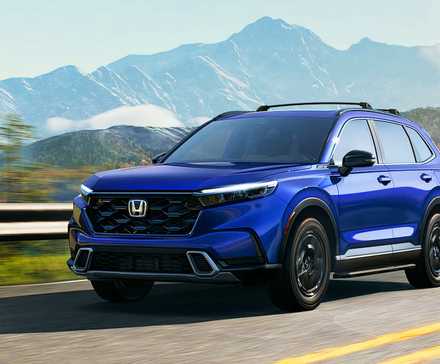 A blue Honda CR-V Hybrid small hybrid SUV is driving on the road. 