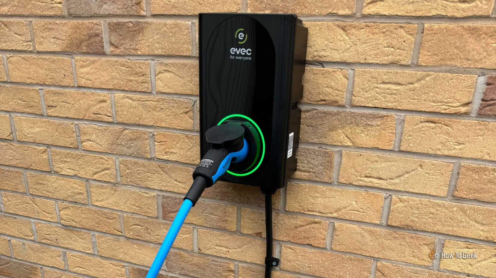 Shot of an evec EV charger mounted on the brick wall of a house.