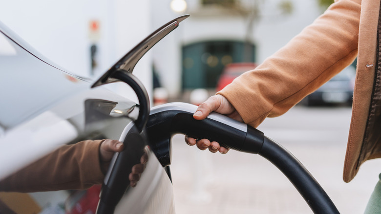 Close up of someone plugging an electric vehicle into a charging station.