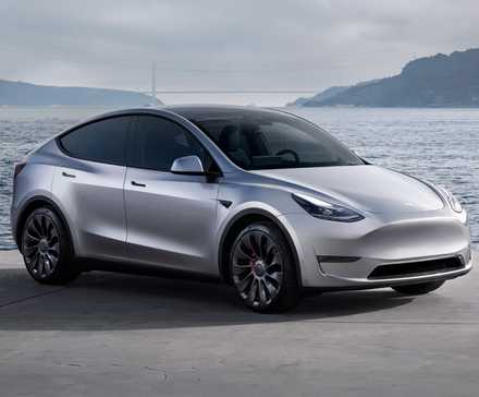 Tesla Model Y in front of a bay on a cloudy day.