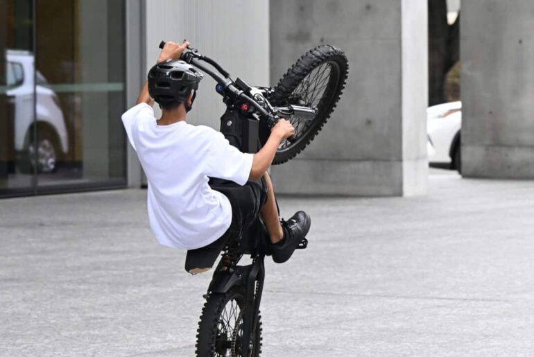 A person riding an e-bike performs a "wheelie"