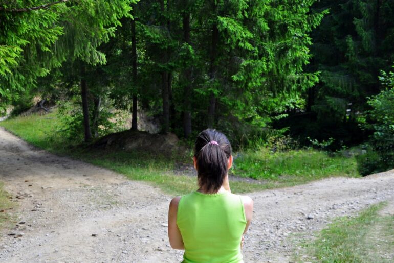 A person standing in front of a fork in the road.