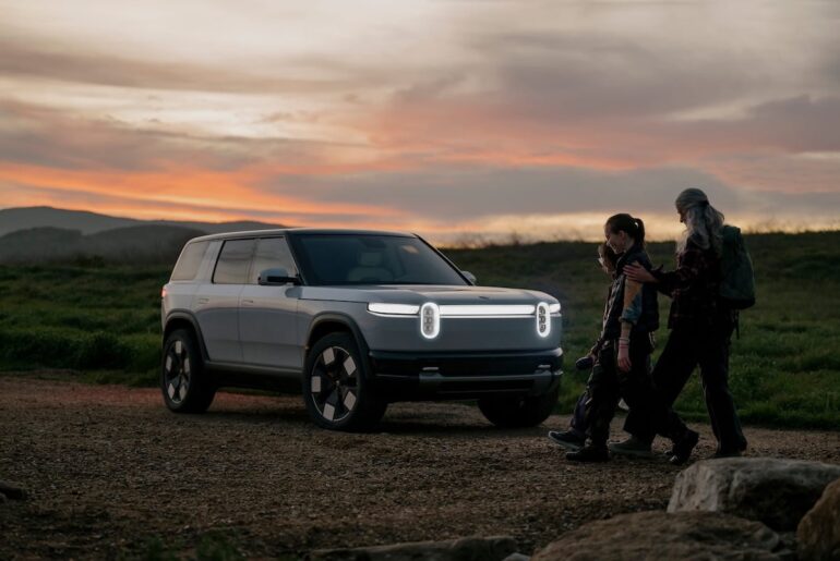 Parent and children walk back to their Rivian R2 at sunset.