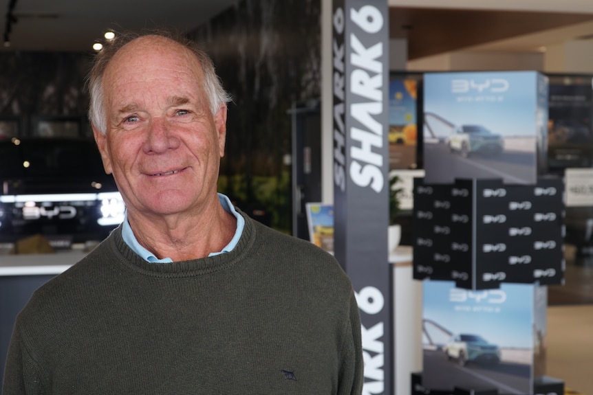 An older man smiles as he looks at the camera.