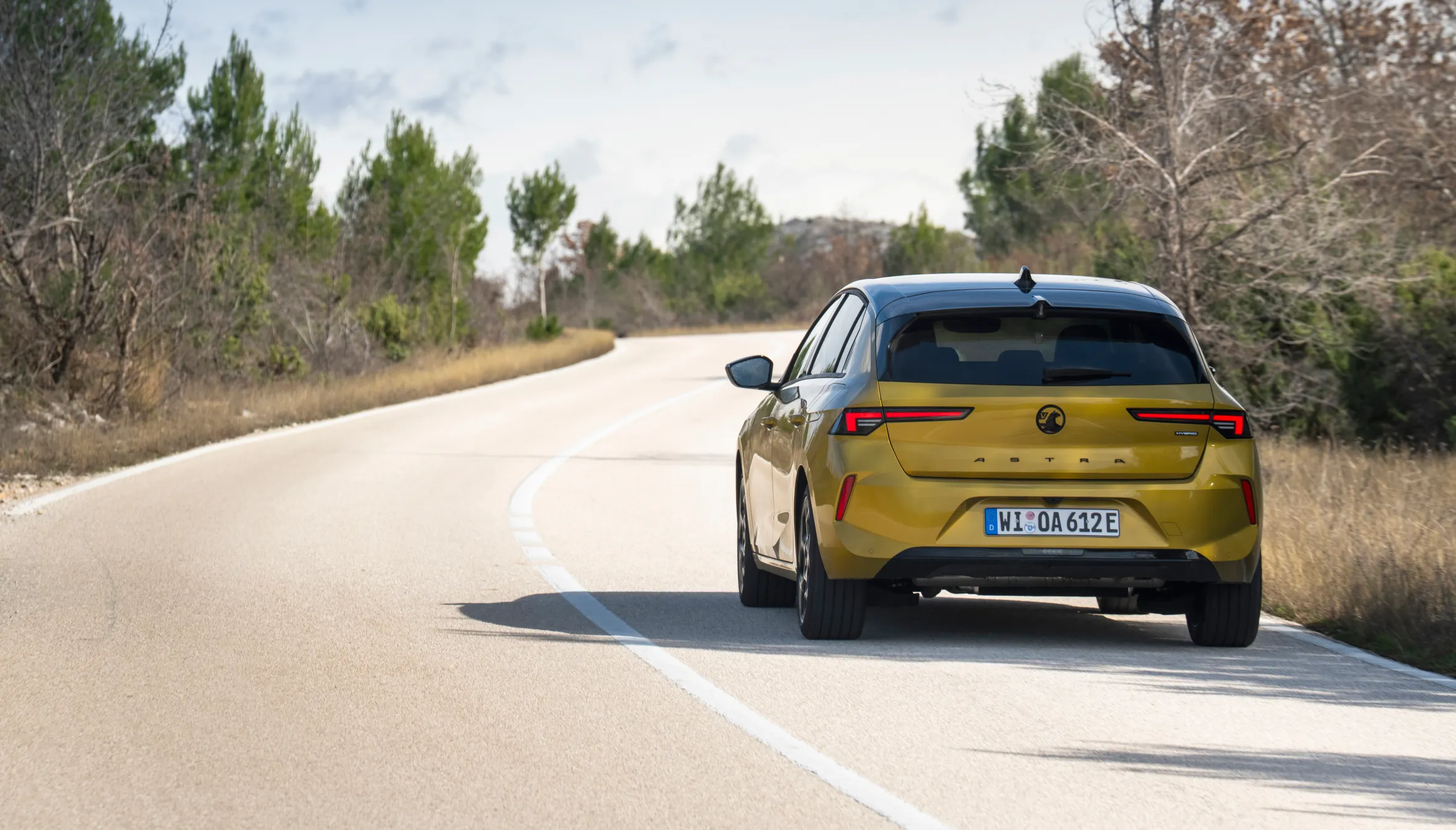 Rear view of a 2026 Vauxhall Astra Hatch on a winding road with trees.