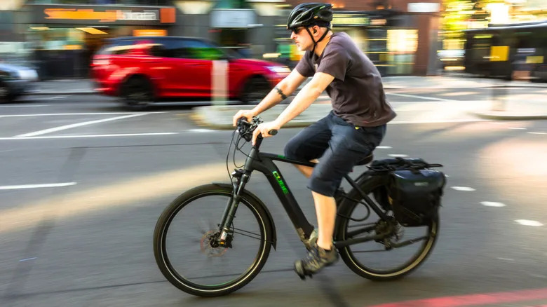 Rider driving fast with e-bike on city street with background a blur.