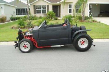 Chevy S10 cab chopped into a rat rod roadster; shortened wheelbase, fenders and bed removed, exposed engine, red headers with side exhaust.