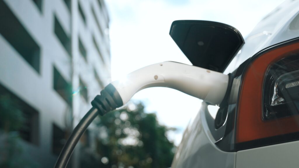 EV electric car charging in green sustainable city outdoor garden in summer. Urban sustainability lifestyle by green clean rechargeable energy of electric BEV vehicle innards