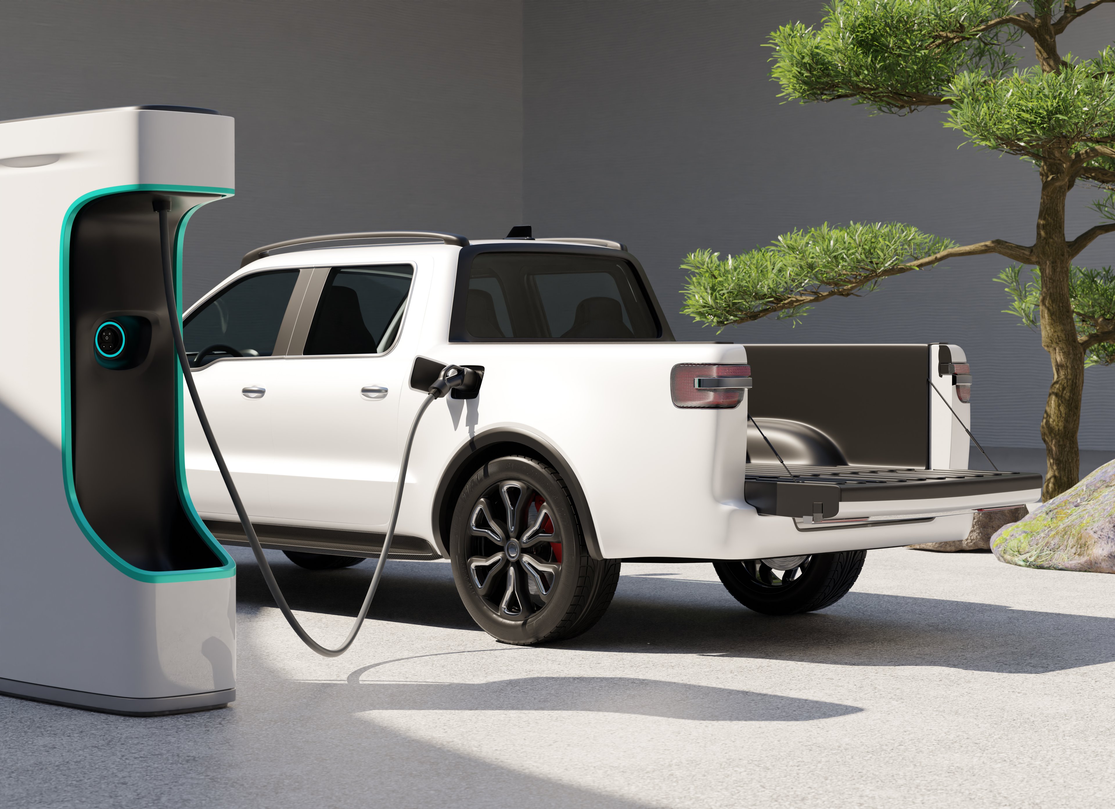 A white electric truck plugged into a charging station.