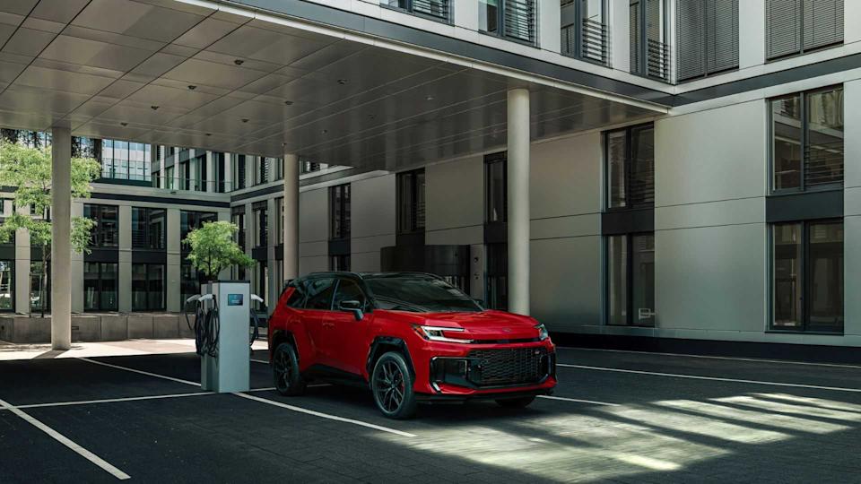 Static front 3/4 shot of a red 2026 Toyota RAV4 PHEV GR Sport charging.