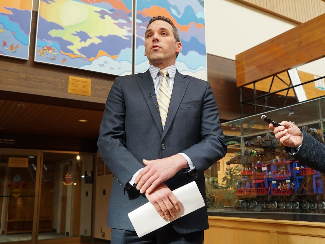 A man in a suit speaks in a media scrum.