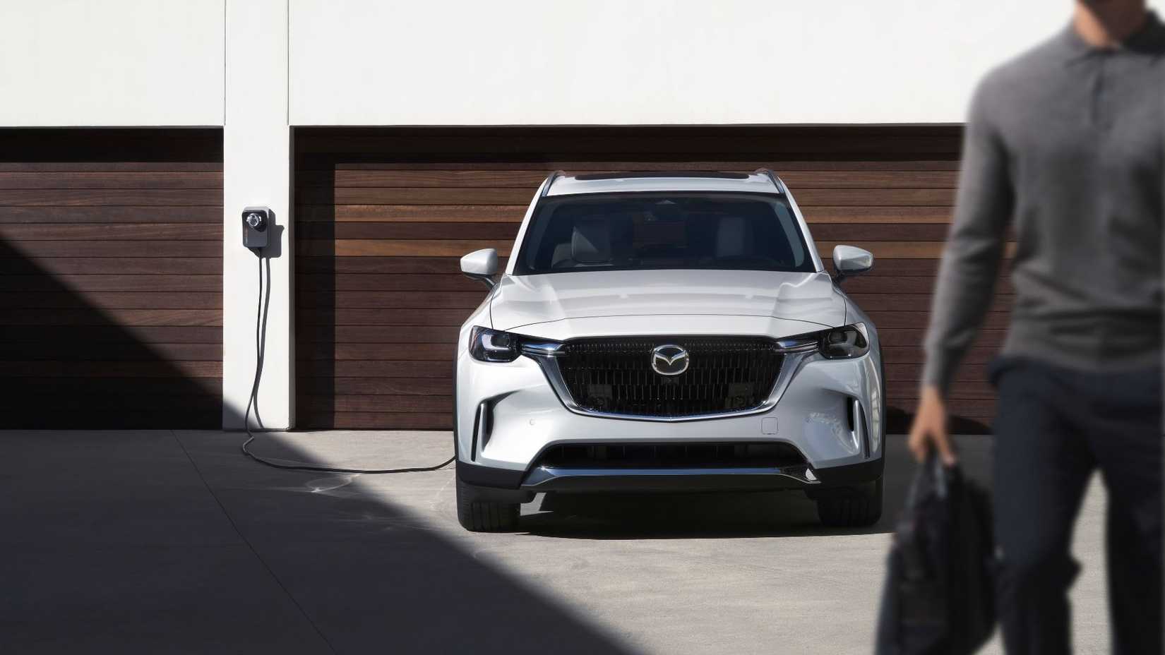 Static front-end shot of a white 2026 Mazda CX-90 PHEV plugged in charging.